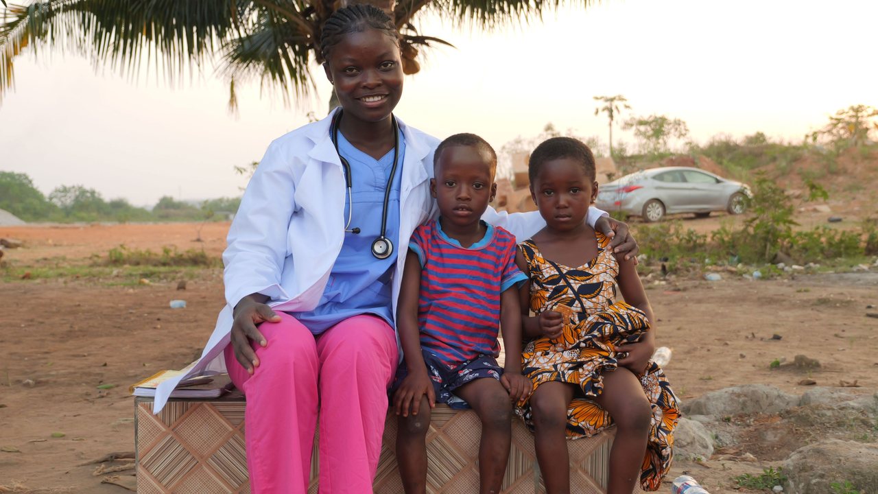 Community health worker sitting outdoors with two children